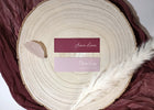 Two name cards on a wooden surface with feathers, placed on a maroon fabric background.