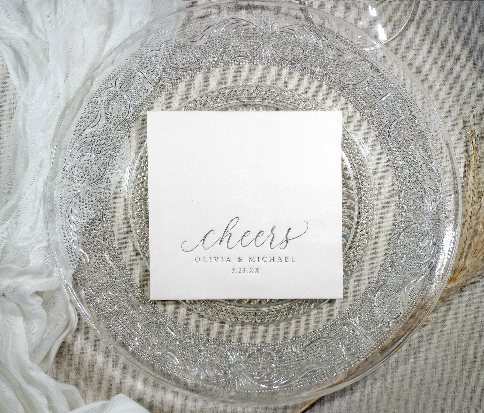 Elegant white cocktail napkin with silver foil text shown on decorative plate