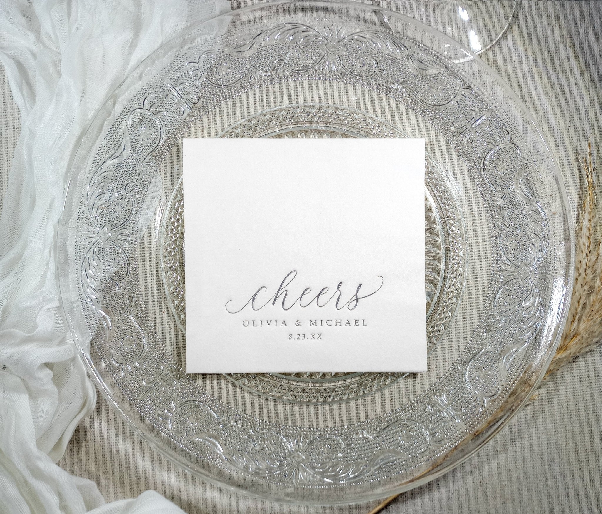 Elegant white cocktail napkin with silver foil text shown on decorative plate