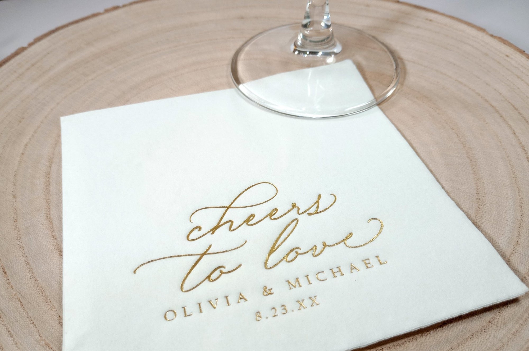 close up of gold foil personalized wedding napkins that say "cheers to love" in an elegant vintage script