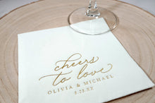 close up of gold foil personalized wedding napkins that say "cheers to love" in an elegant vintage script
