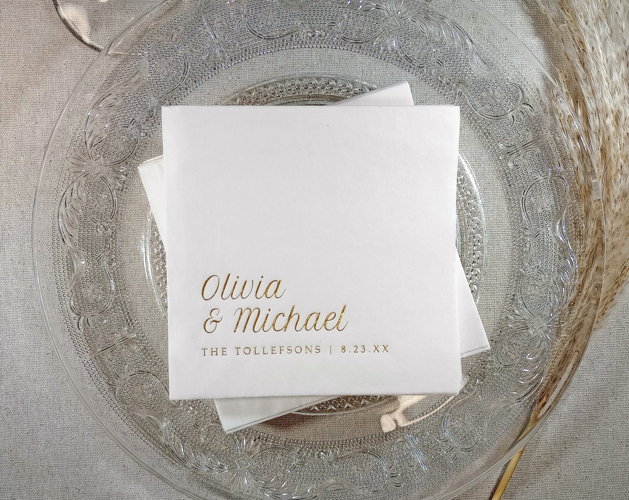 White foil stamped napkins with gold foil names on a decorative glass plate