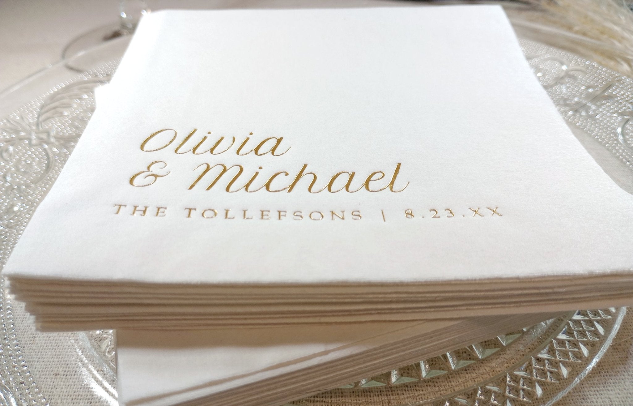 Stack of white napkins with gold text on a glass surface
