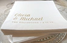 Stack of white napkins with gold text on a glass surface