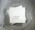 White wedding cocktail napkin with “So We Met at a Bar” in elegant gold foil and custom names below