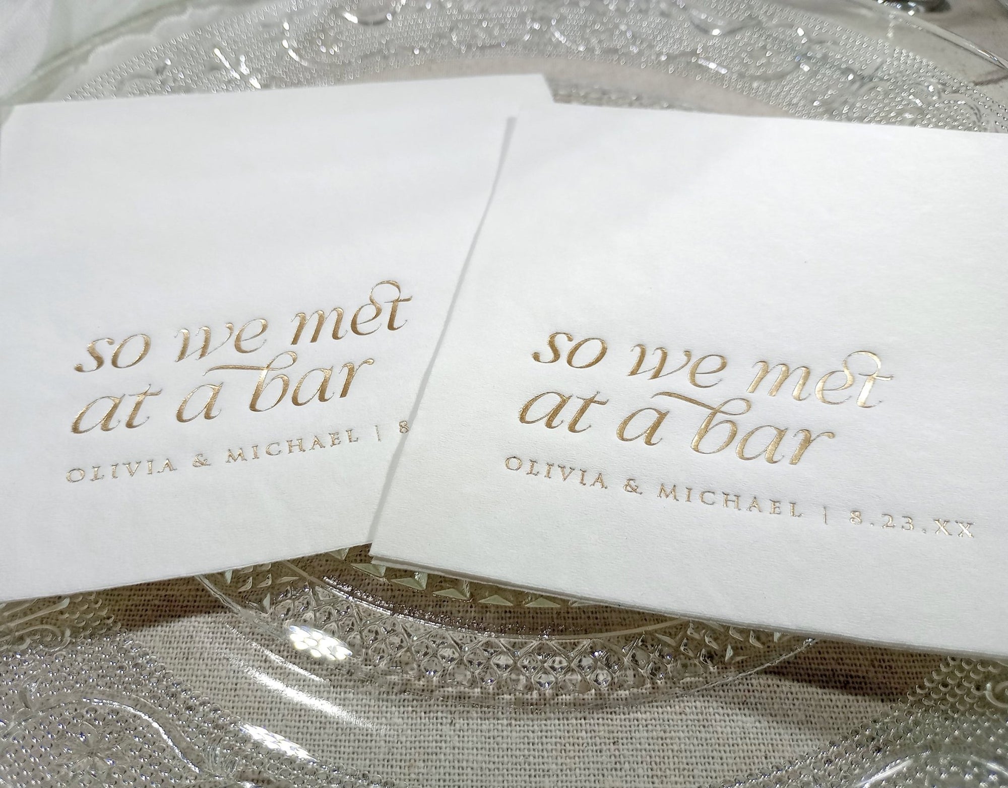 Close-up of gold foil “So We Met at a Bar” napkin placed on a reception table setting
