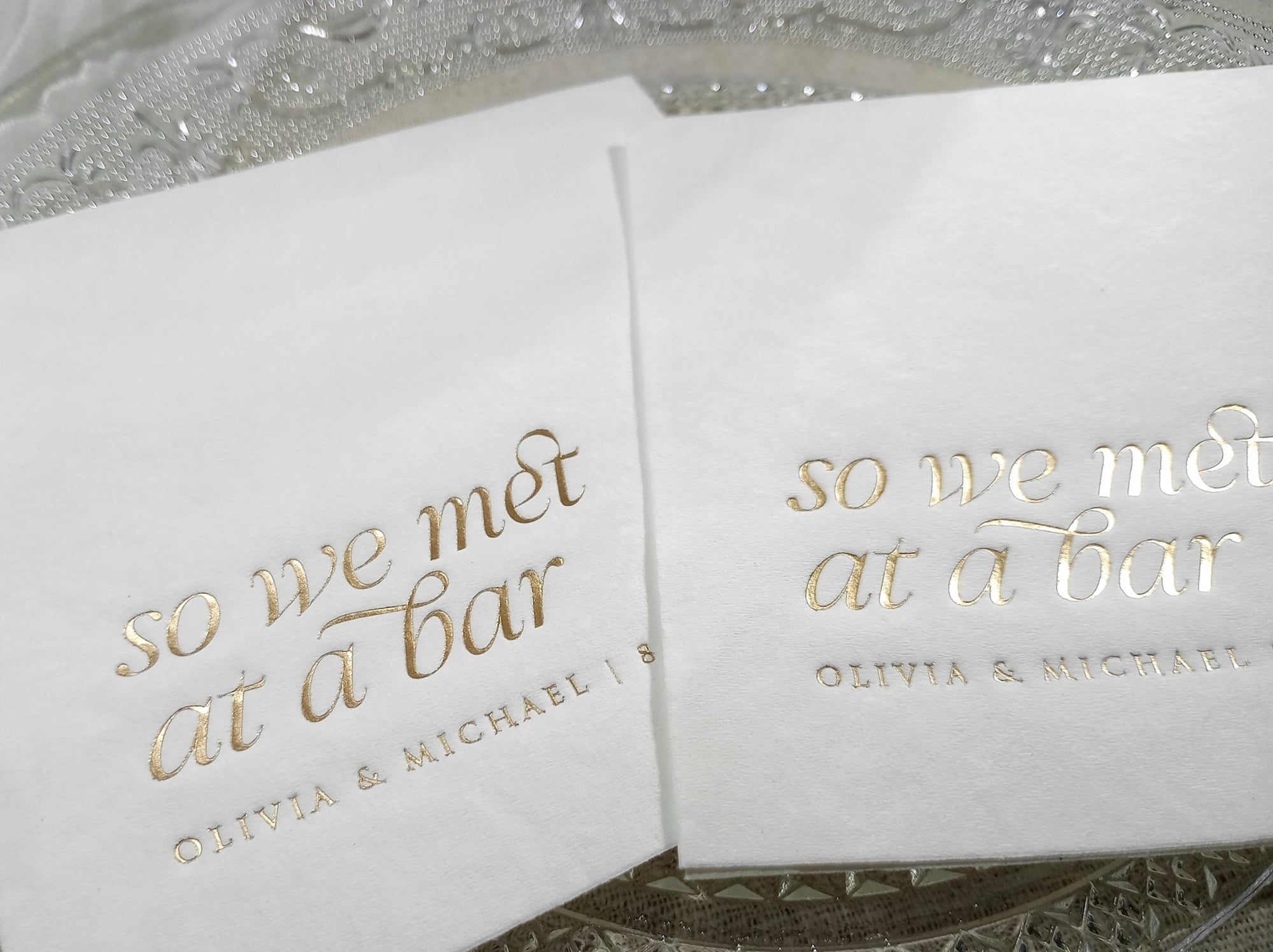 Close-up of gold foil stamped “So We Met at a Bar” napkins placed on a reception table setting