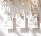 Three table assignment cards hanging on a string with decorative elements.