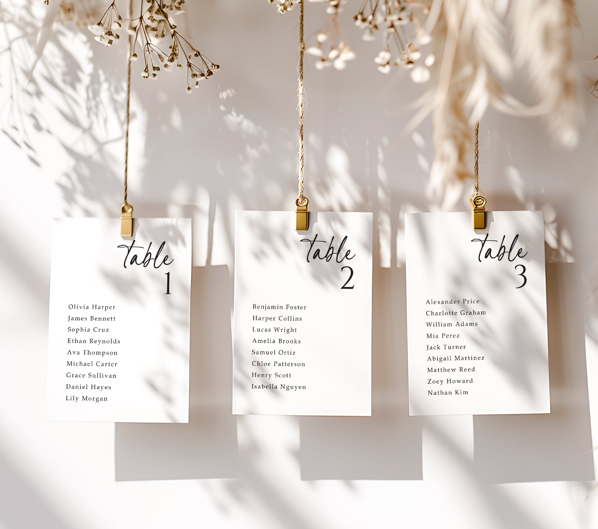 Three table assignment cards hanging on a string with decorative elements.