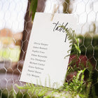 Table assignment card with names on a wire fence background