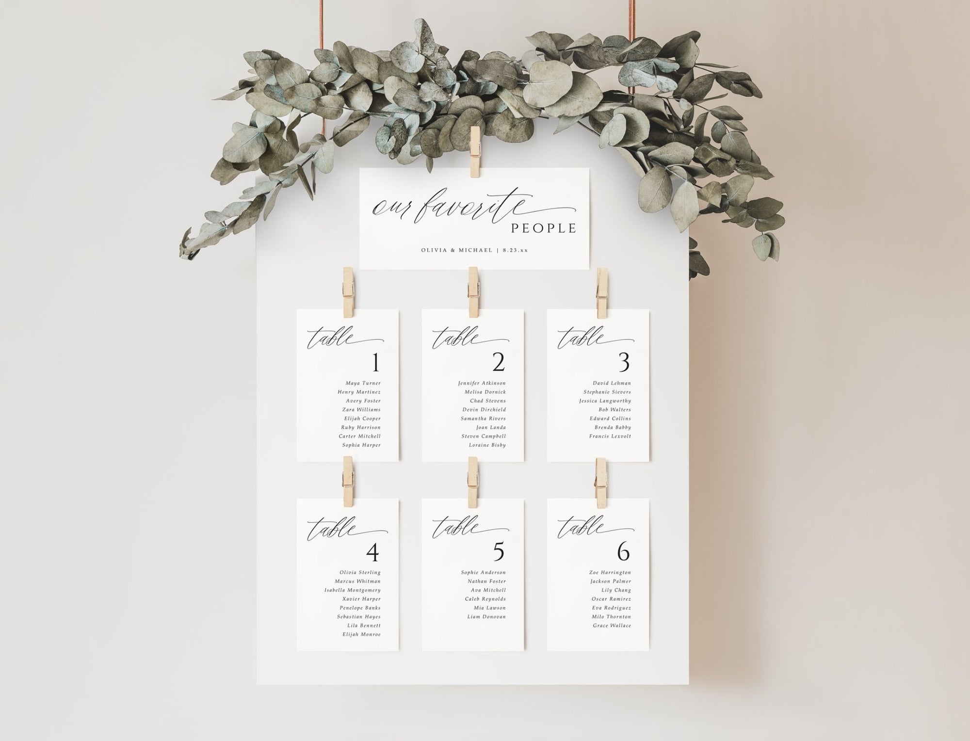 Modern calligraphy wedding seating cards arranged on a white frame with floral accents and header card.