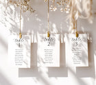 Three table assignment cards hanging on a string with gold clips against a neutral background.