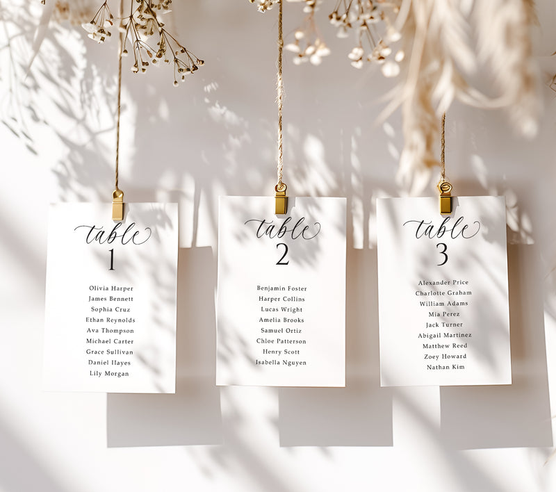 Three table assignment cards hanging on a string with gold clips against a neutral background.