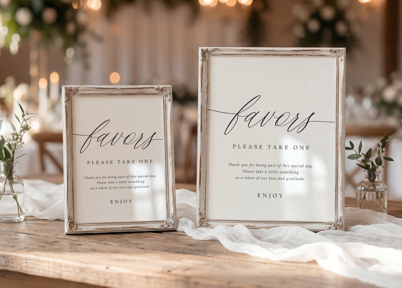 Two framed printed wedding favors signs on a wooden table, one larger and one smaller, both with elegant black script text on a white background and distressed silver frames.