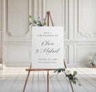 foam board wedding welcome sign with script names and serif text, styled on easel with floral accents