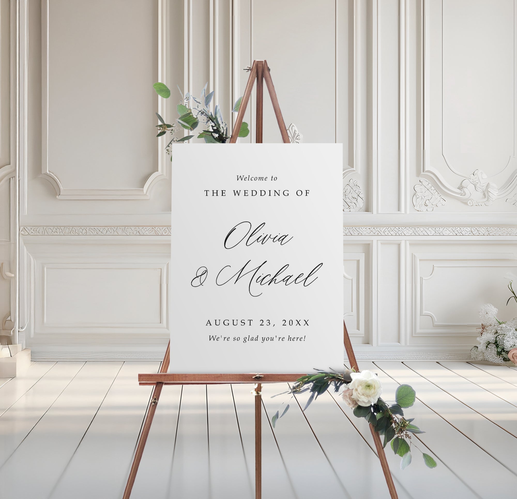foam board wedding welcome sign with script names and serif text, styled on easel with floral accents