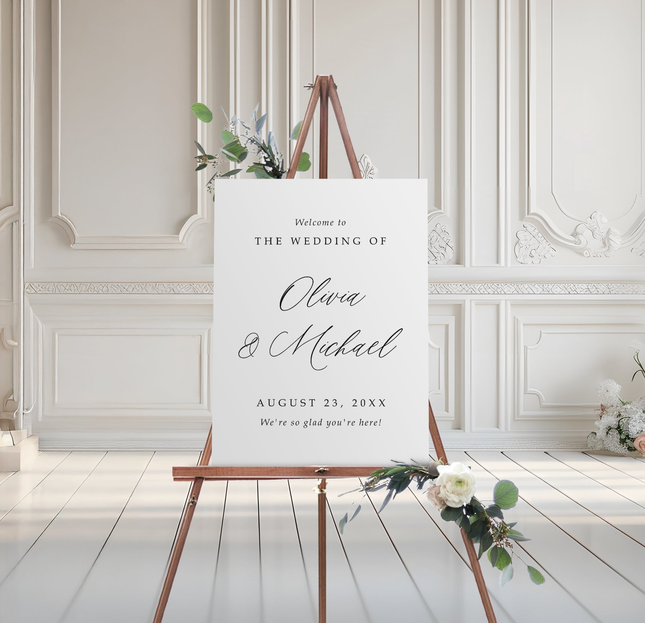 foam board wedding welcome sign with script names and serif text, styled on easel with floral accents
