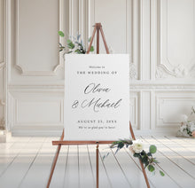 foam board wedding welcome sign with script names and serif text, styled on easel with floral accents