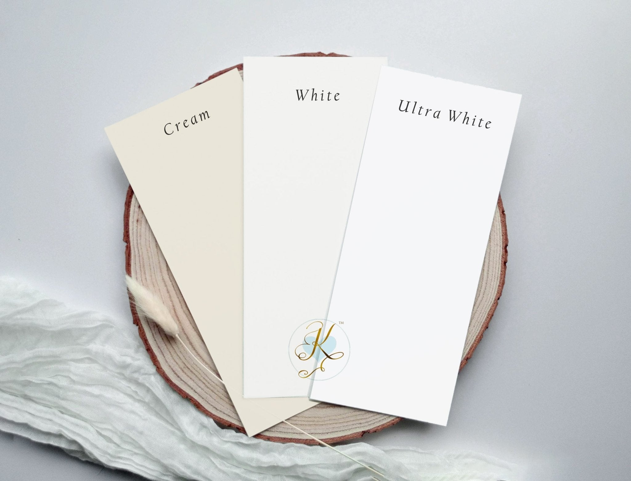 Three sheets of paper labeled 'Cream', 'White', and 'Ultra White' on a wooden board.