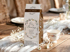 Bridal shower prize (roasted coffee box) with floral design and teacup on a wooden table.