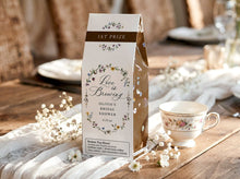 Bridal shower prize (roasted coffee box) with floral design and teacup on a wooden table.